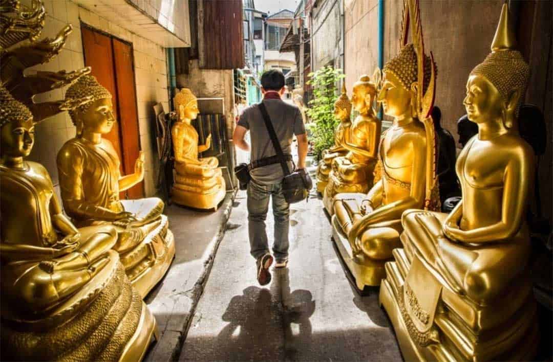 touriste courant a travers 2 rangées de Bouddhas